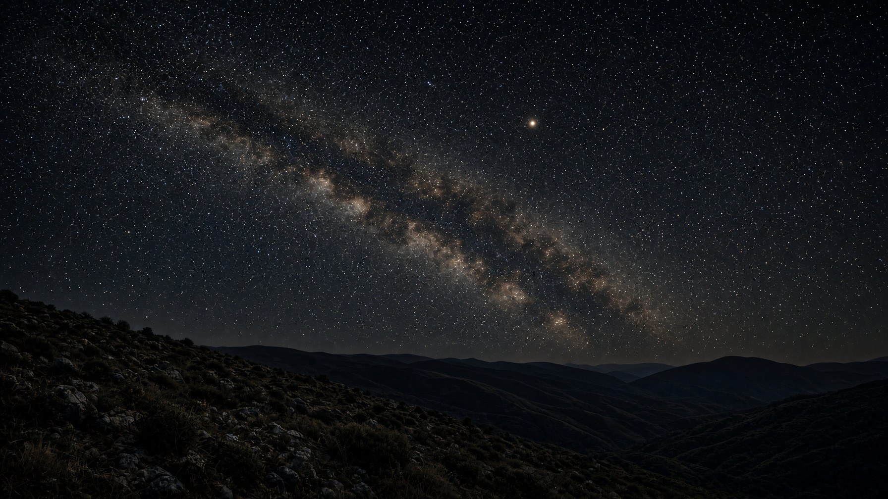 A naked-eye night sky over a dark hill, one slow cream wanderer among fixed stars