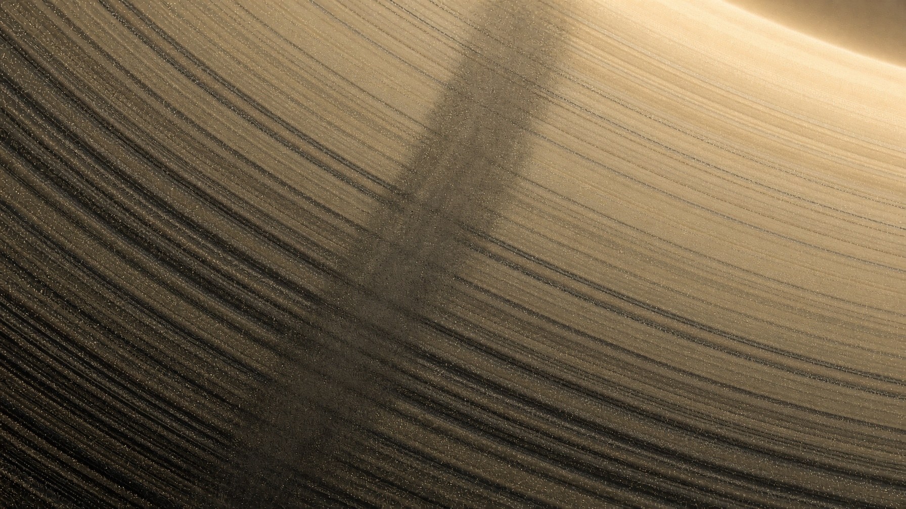 Close view of Saturn’s B ring as thousands of ringlets with a dark radial spoke of fine ice